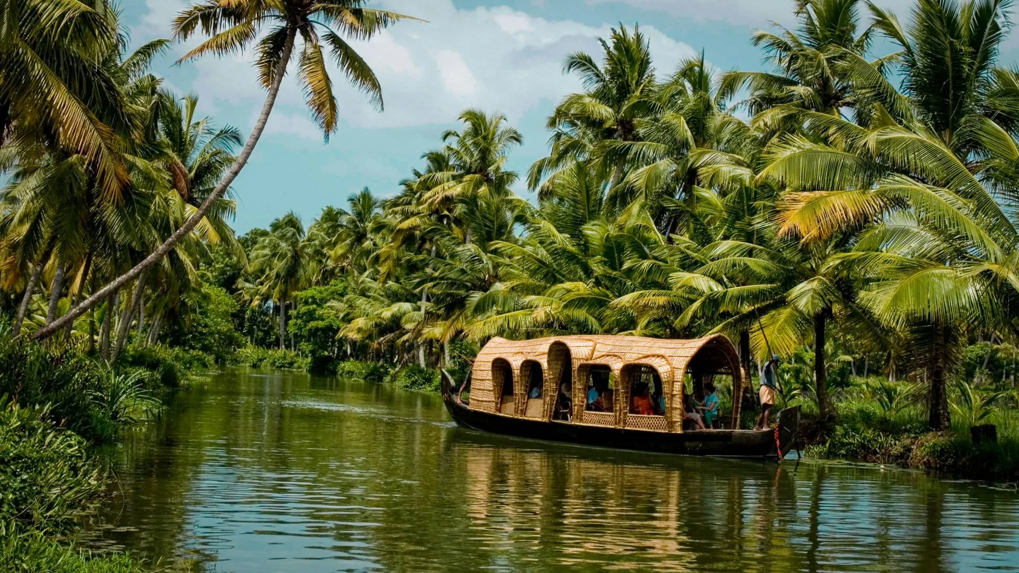 A traditional kettuvallam houseboat gliding along a palm-lined canal on the Kerala backwaters